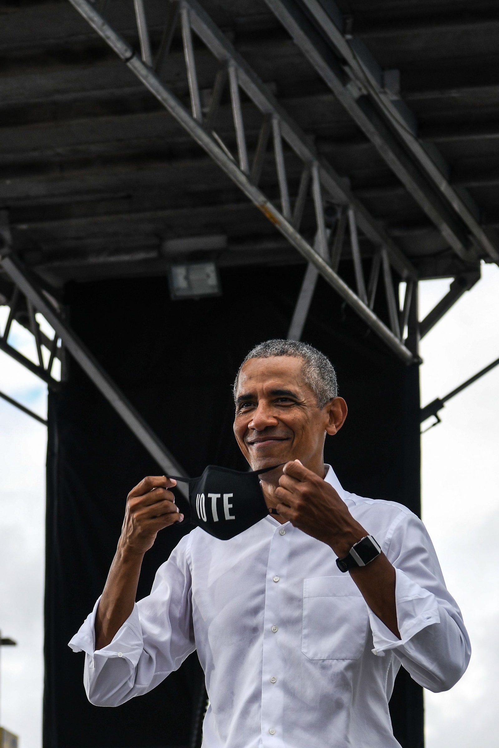 Barack Obama putting on a face mask that says vote