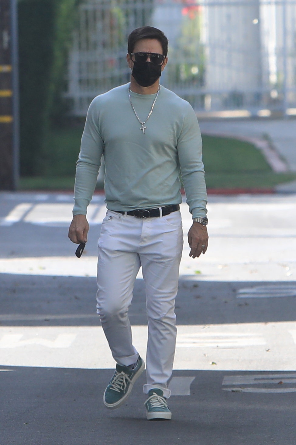 Mark Whalberg on a walk in a green shirt and white pants