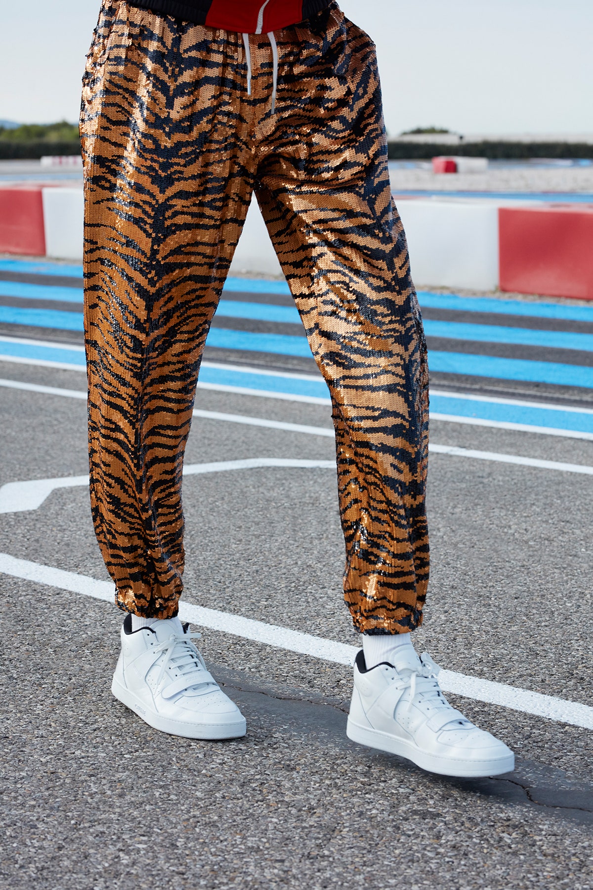 A close up of a model wearing tiger stripe pants and white celine sneakers