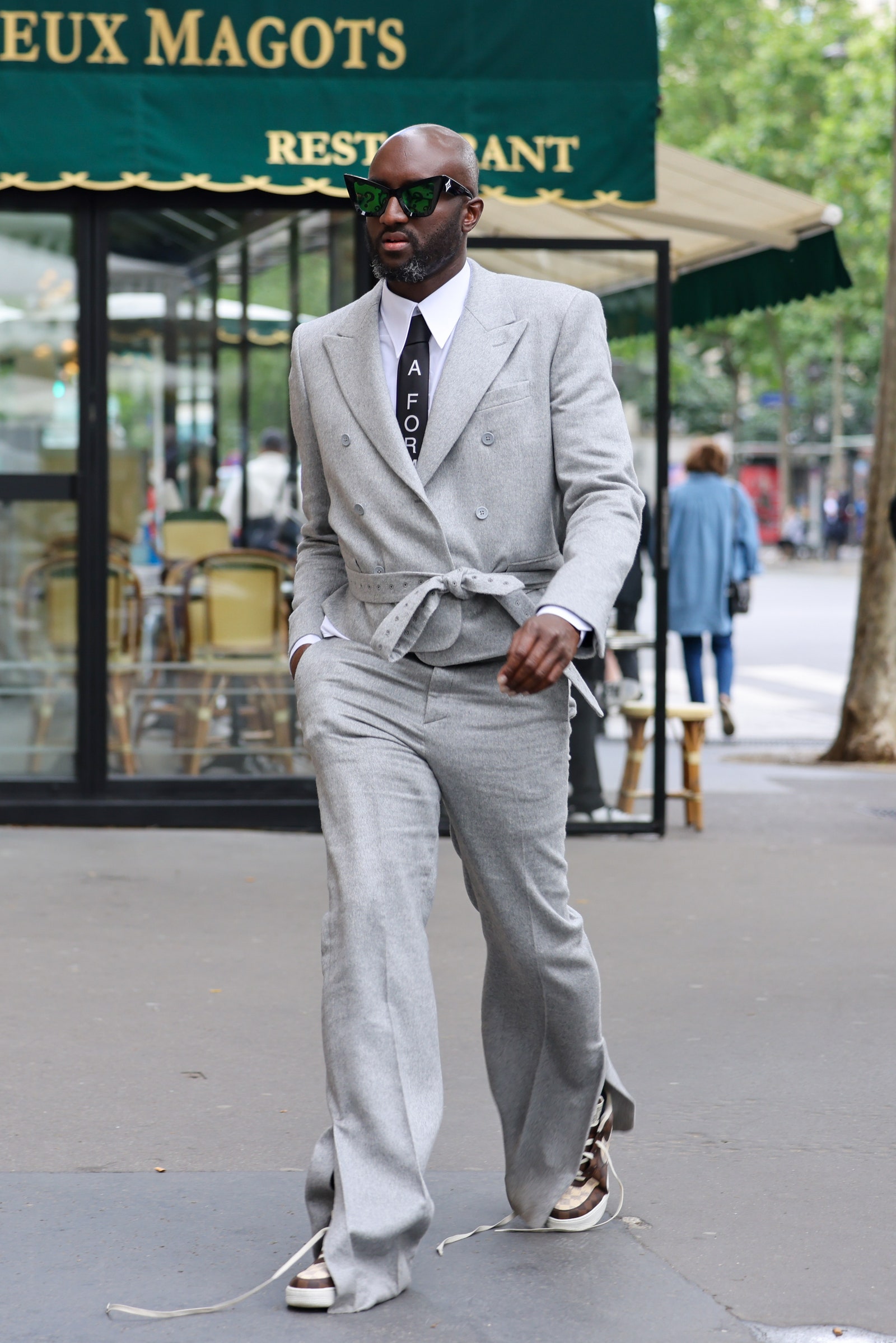Image may contain Clothing Apparel Suit Coat Overcoat Human Person Sunglasses Accessories Accessory and Tie