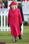 Image may contain: Elizabeth II, Clothing, Apparel, Hat, Coat, Overcoat, Human, Person, Suit, Grass, and Plant