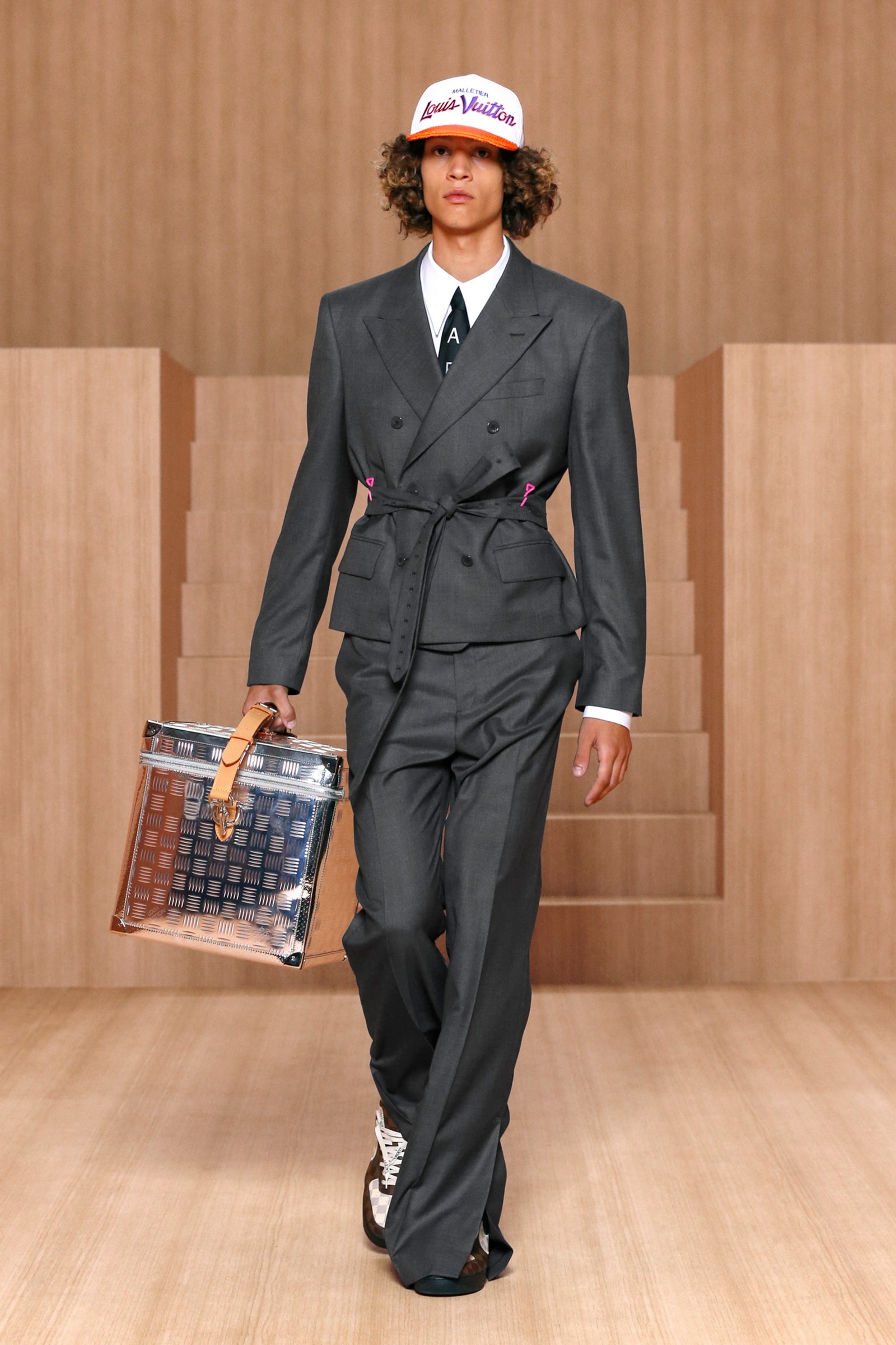 A person wearing a grey suit with grey flared pants