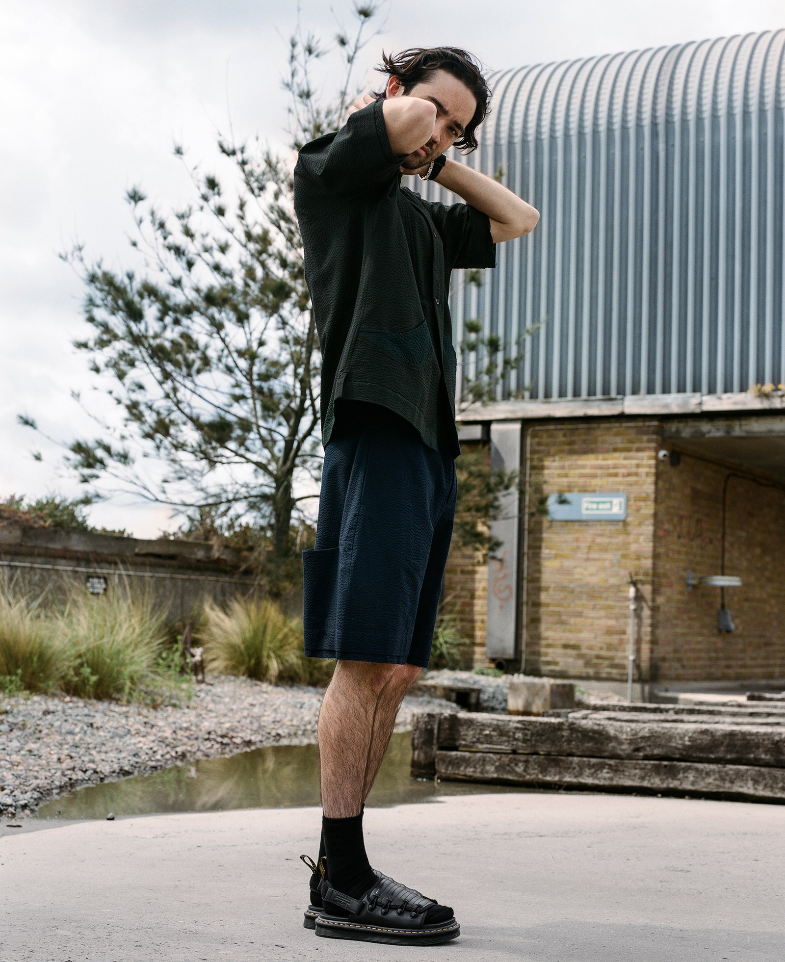 A man wearing blue shirts a black t shirt and black leather sandals